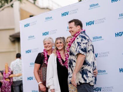 Four vacationers with leis take a photo at an HGV Live! concert in Hawaii