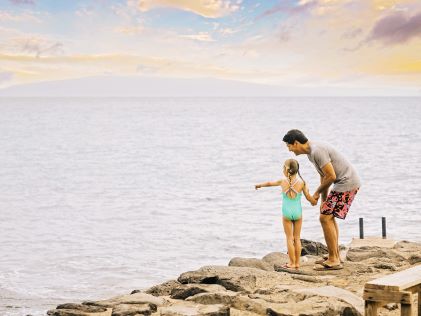 A father and daughter look over the ocean in Maui, Hawaii