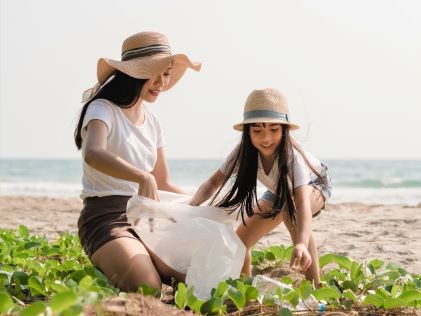 A mother and daughter picking up trash from a beach 