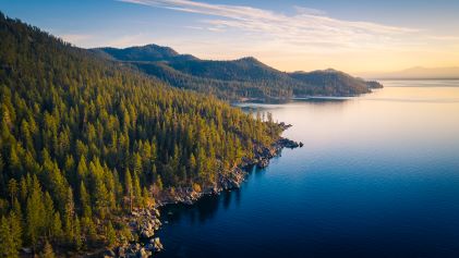 Beautiful aerial image, lush forest meets water's edge, sunrise painted sky, South Lake Tahoe, California. 