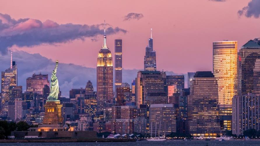 Iconic New York City skyline, Statue of Liberty, New York Bay, purple dusk sky, New York. 