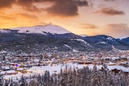 Picturesque aerial image, snow-covered mountain town, snow-capped mountains in distance, sunset set painted sky overhead, Breckenridge, Colorado. 