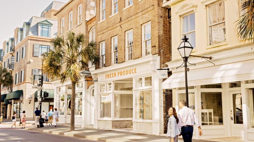 Couple strolling, storefront-lined main street, Charleston, South Carolina. 