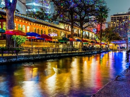 Colored lights and businesses next to the river at night in San Antonio, Texas