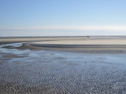 Two people in the distance walk on the beach of St. Simons Island, Georgia