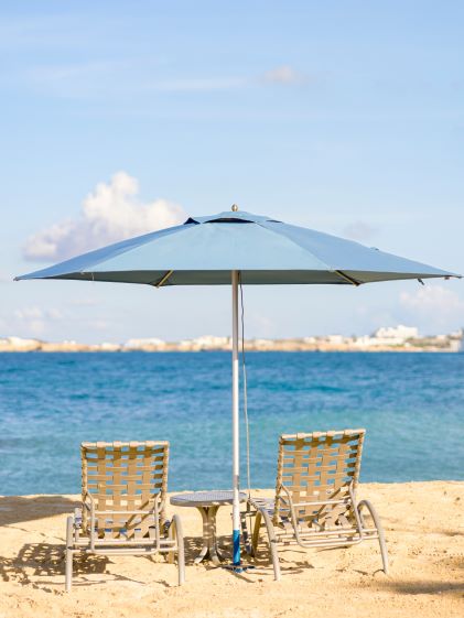Two lounge chairs under an umbrella on the beach