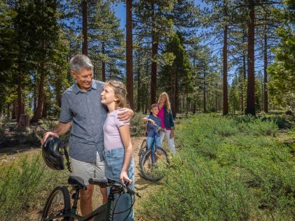 Grandparents and grandchildren walk with their bikes in the forest surrounding South Lake Tahoe