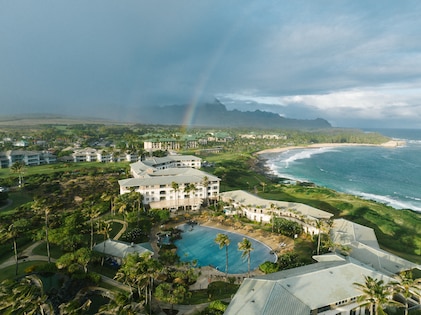 An aerial shot of a rainbow over the lush grounds and beachfront at The Point at Poipu, a Hilton Vacation Club, Koloa, Hawaii