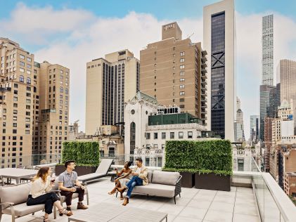 A group of people sitting on a furnished terrace at The Quin, a Hilton Club, one of Hilton Grand Vacations' New York timeshares