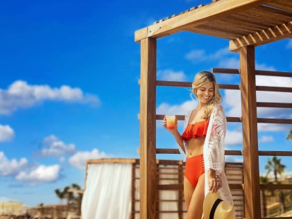 A woman with a drink at a beachside cabana at La Pacifica Los Cabos, a Hilton Club in Mexico