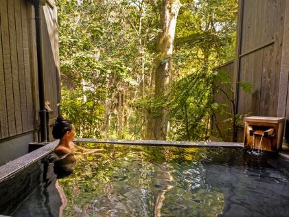 A woman in a hot spring at a spa in The Bay Forest Odawara, a Hilton Club