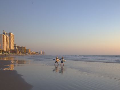 Two surfers head to the ocean at sunrise at Daytona Beach, Florida