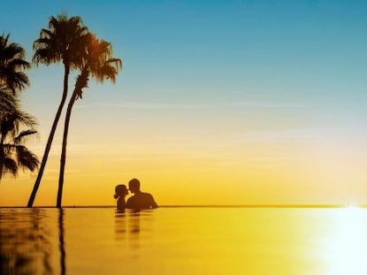 A couple cuddles in the pool at sunset