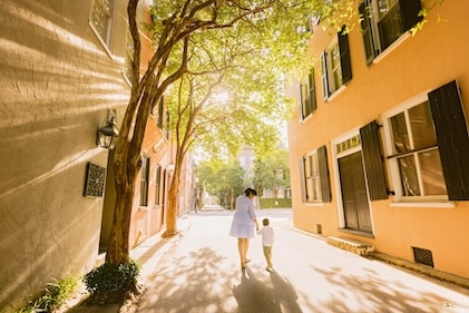 Mother and child walking along sunwashed street during the golden hour in Charleston SC.