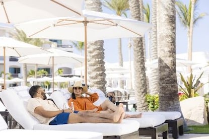 Couple lounging poolside, Hilton Grand Vacations resort. 