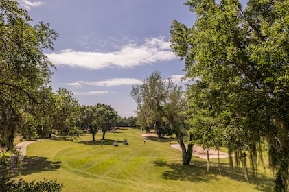 Long shot of Mystic Dunes Golf Club in Orlando, Florida featuring greens and mature trees under blue skies.
