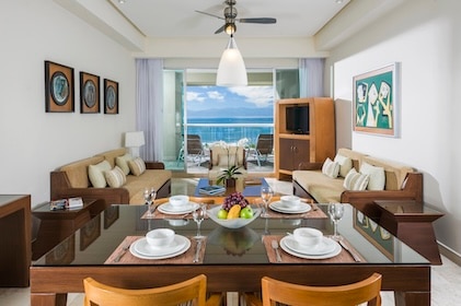 View from inside a Suite looking out from the dining area through the living room and patio doors with the balcony and blue sea as skies beyond at The Grand Mayan Nuevo Vallarta resort in Mexico