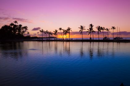 Romantic sunset skies over calm, palm-tree lined lagoon, Big Island, Hawaii. 