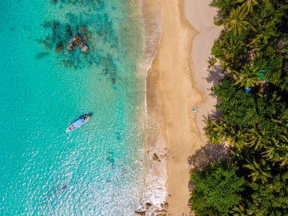Overhead image, clear water washes shore golden sands, lush green forest, blue skies, Banana Beach, Phuket, Thailand. 