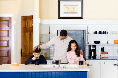 Man, two children, happily  interacting over snacks, beautiful kitchen, Tremblant, a Hilton Grand Vacations Club, Mont Tremblant, Canada. 