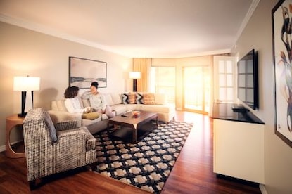 Two women talking, drinking coffee, spacious living room, Parc Soleil, a Hilton Grand Vacations Club, Orlando, Florida.