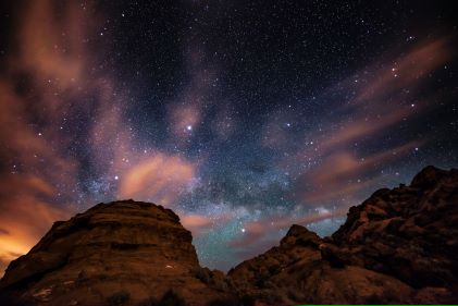 Stunning desert night sky, glowing milky way stars above desert rocks, American Canyonlands, Utah. 