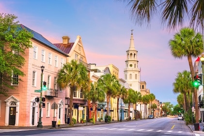 Street level view down the road of historic pastel-colored homes and palm trees at dusk.