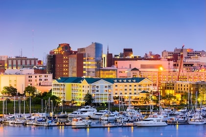 View of power boats lining the Charleston, SC harbor and the buildings beyond. Blue water is in the foreground and blue skies are overhead.