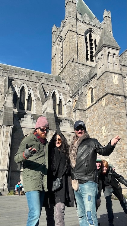 Hilton Grand Vacation Members standing and smiling in front of a gray stone cathedral on their vacation.