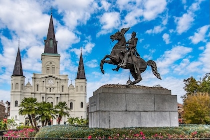 Daytime view of Jackson Square in New Orleans with General Andrew Jackson's statue in the foreground and Saint Louis Cathedral in the background.