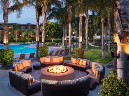 Outdoor lounge area, fire pit, hammocks, palm trees, dusk, MarBrisa, a Hilton Grand Vacations Club, California. 