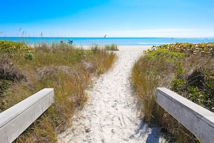 Sanibel, Florida white sand beach path to the water with the path surrounded by grassy areas.