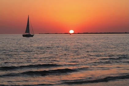 Sailboat sunset cruise with deep orange sky views from the water around Sanibel Island.