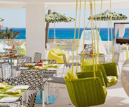 Green swinging chairs on colorful outdoor patio overlooking the Pacific Ocean at Mio Restaurant at La Pacifica Los Cabos, a Hilton Club
