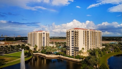 Aerial view of Parc Soleil, a Hilton Grand Vacation Club in Orlando, Florida under blue skies dotted with white clouds and tree-lined lakes in the foreground.