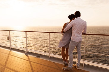 Couple on the upper deck of a cruise ship watching the sunset.