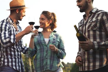 Happy wine tourists tasting wine in vineyard