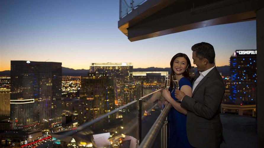 Couple enjoying the balcony at a Hilton Grand Vacations Las Vegas resort. 