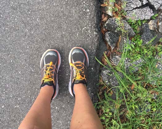 A first person perspective shot of a runner wearing sneakers on a running trail. 