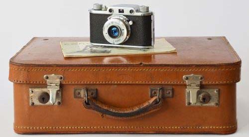 Picture of a classic suitcase with an vintage camera on top. 