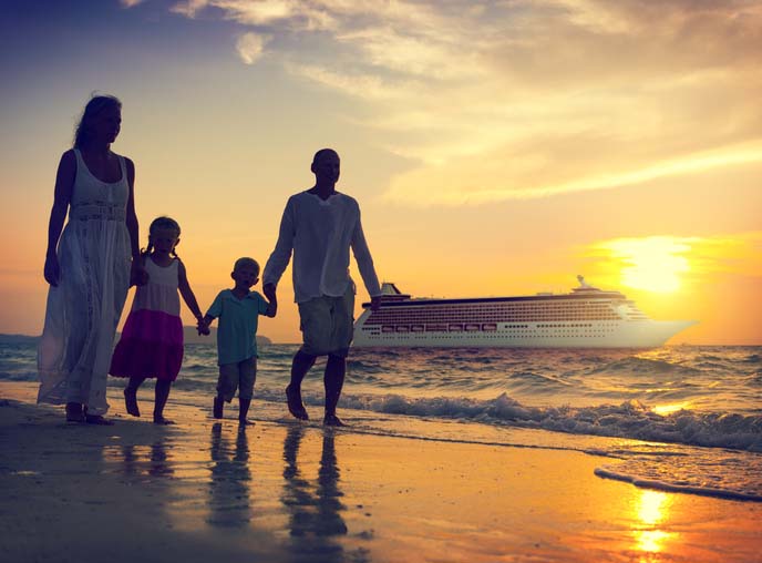 Silhouette of family holding hands and walking on the shoreline at sunset. 