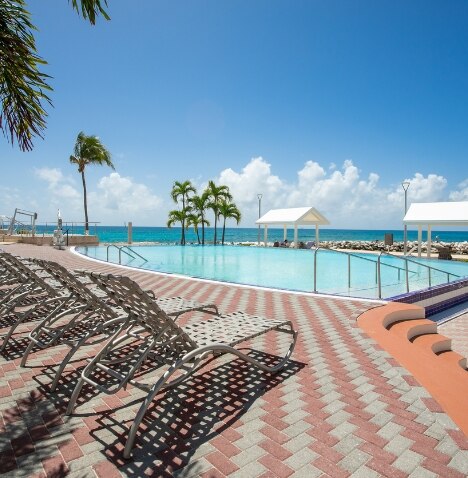 Lounge chairs sit around the beach with a view of the Caribbean waters.