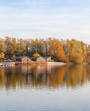 Tranquil Lake with fall foliage and cabins on the far shore