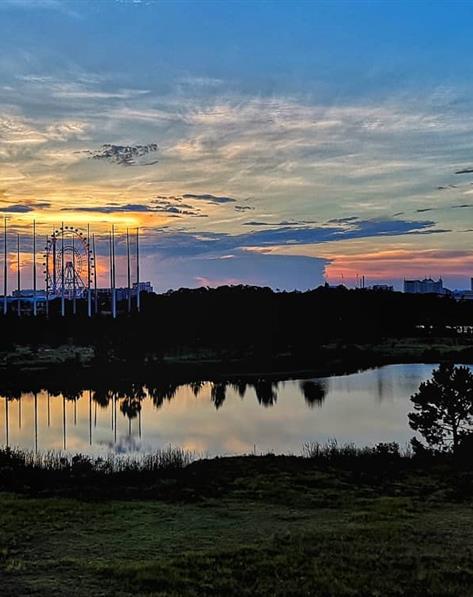 Instagram photo of the sun setting over a ferris wheel, golf range, lake, resorts and restaurants on I-Drive in Orlando, Florida.