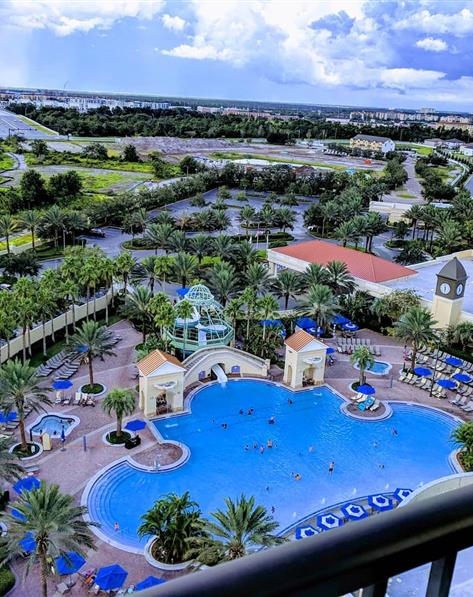 View from a balcony of the pool, lounge area and surrounding trees at Parc Soleil, a Hilton Grand Vacations Club located in Orlando, Florida.