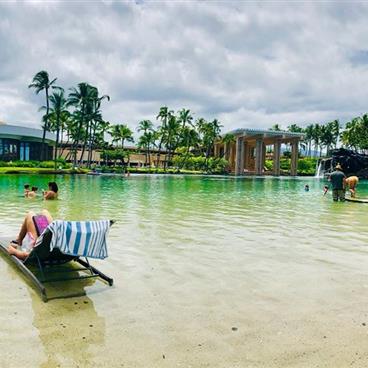 People lounging and playing in a lagoon in Hawaii.
