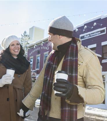 Couple drinking hot drinks and walking through town.