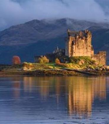 Scottish castle along a lake with mountains in the background