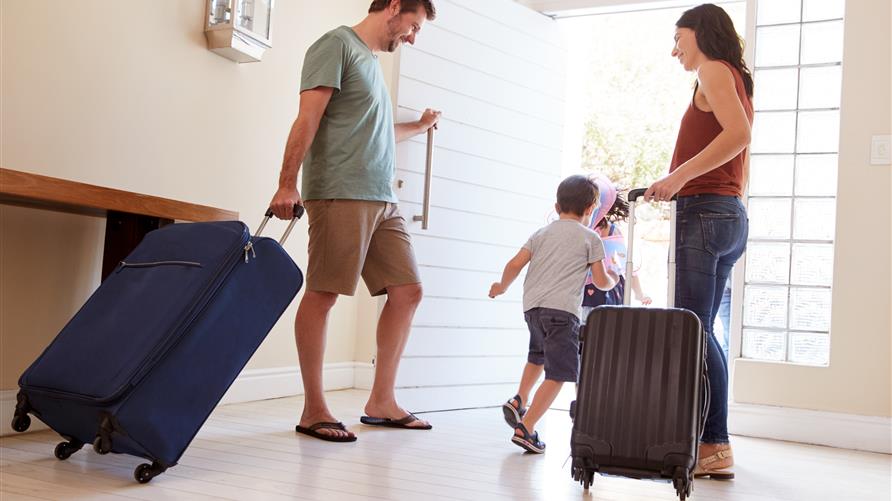 Excited family with luggage walking out the door for an extended vacation.