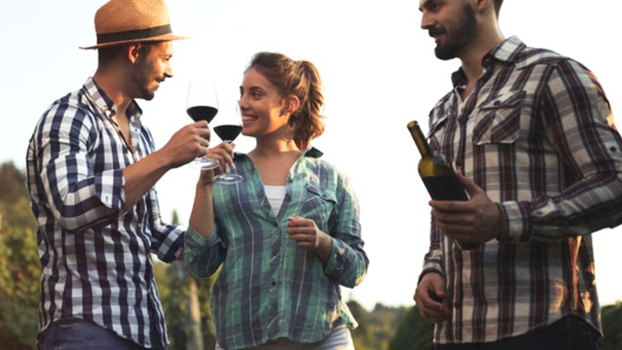 Happy wine tourists tasting wine in vineyard